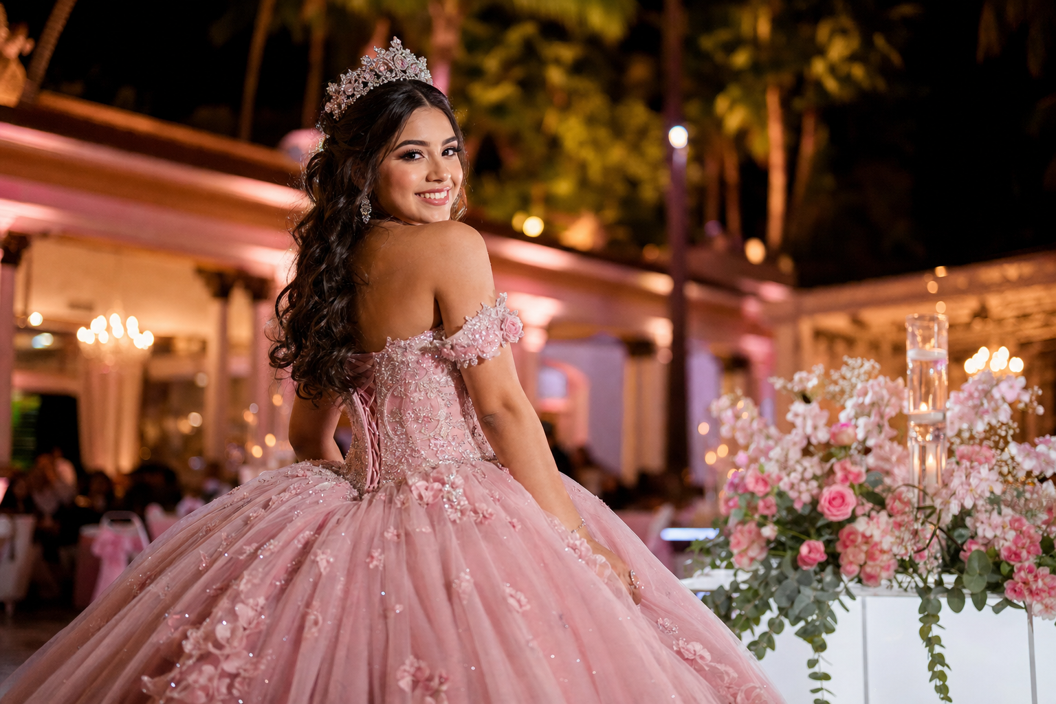 Quinceañera en vestido rosa con tiara en salón de fiesta decorado